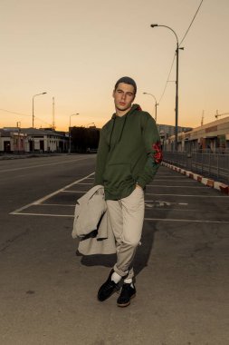 Şık giysiler içinde Yakışıklı adam gün batımında bir şehir caddesinde yürüyor