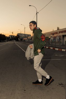 Şık giysiler içinde Yakışıklı adam gün batımında bir şehir caddesinde yürüyor