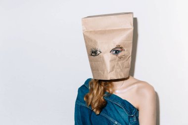 Kot pantolon beyaz bir duvarın arka planına karşı kafasına bir paket ile güzel bir kızın Yaratıcı portre