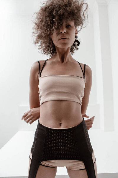 Beautiful girl with curly hair in sports underwear on a white background