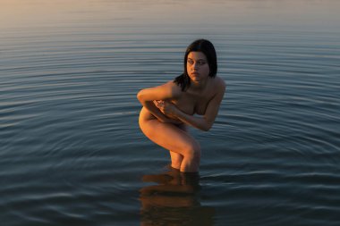 Doğada günbatımında şık giyinmiş şık bir kız. Kum, göl ve orman.