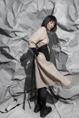 Soyut bir arka planda şık, minimalist kıyafetler giyen moda kızı.