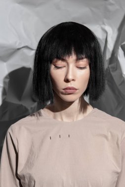 Soyut bir arka planda şık, minimalist kıyafetler giyen moda kızı.