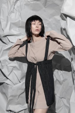 Soyut bir arka planda şık, minimalist kıyafetler giyen moda kızı.