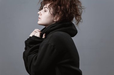 Gri arkaplanda kızıl saçlı güzel kıvırcık saçlı bir kızın portresi.