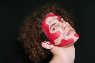 Cadılar bayramı için makyajlı bir erkek stüdyo resmi. Yüzünde soyutlama ve bir sürü göz..