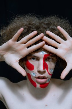 Cadılar bayramı için makyajlı bir erkek stüdyo resmi. Yüzünde soyutlama ve bir sürü göz..