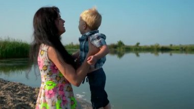 Mutlu güzel annem çocuk el ve iplik etrafında çember üzerinde alır. Neşeli pozitif duygular aşk. Yaz nehir Gölü sabah güneşli gün mavi gökyüzü. Yavaş hareket 30 p 0,5 60 p