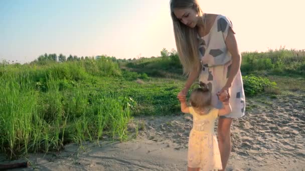 若く美しい母親と彼女の子供は 再生し 川の近くを歩きます 夏湖朝晴れた青い空 スローモーション — ストック動画