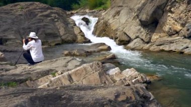 Atış kaydırma. Kameramanların doğa filme buzlu dağ Nehri yakınında oturuyor. Film yapımcısı kamera operatörü. Yavaş hareket 4k 30p 0,5 hızı 60 p