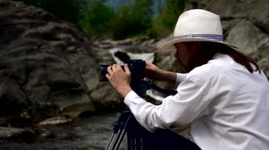 Yakın çekim kameramanların görüntüleri buzlu dağ Nehri yakınında vuruyor. Film yapımcısı kamera operatörü. Yavaş hareket 4k 30p 0,5 hızı 60 p