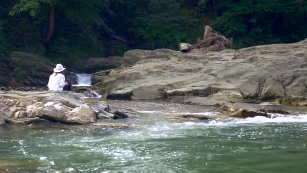 ビデオ撮影は 山川の近くの岩の上の映像を撮影します 映画カメラの演算子です のスローモーション — ストック動画