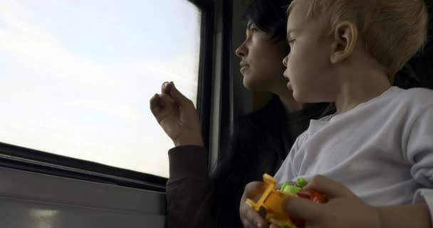 带着孩子的疲惫的小母亲望着窗户 贫穷的难民家庭旅行由旧肮脏的预算郊区火车 客运服务 — 图库视频影像