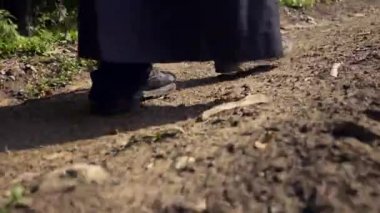 Yakın çekim Ayak kırsal kirli yolda. Siyah pelerin palto gizemli adam göçebe. Monk Traveler dağ orman kırsal yolu üzerinde yürüyor