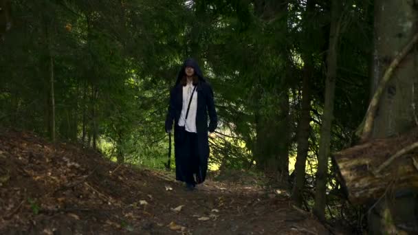 中世纪神秘流浪的人在黑色斗篷外套与胡德走在森林里 在山里的怪物旅行 — 图库视频影像