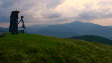 Fotoğrafçı güzel manzara dağın zirvesinde vuruyor. Bulutlar filme kameramanların Meadows Woods