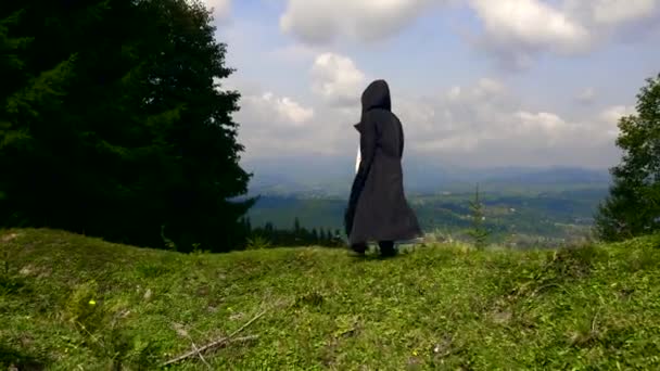僧人传教士旅行到遥远的土地 神秘的流浪者在山顶上旅行 男人在黑色斗篷外套与帽子 — 图库视频影像