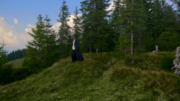 僧人传教士旅行到遥远的土地 神秘的流浪者在山顶上旅行 男人在黑色斗篷外套与帽子 — 图库视频影像