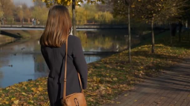 60P Kaunis Tyttö Kääntyy Taaksepäin Kävellä Syksyllä Puistossa Lähellä Järveä — kuvapankkivideo
