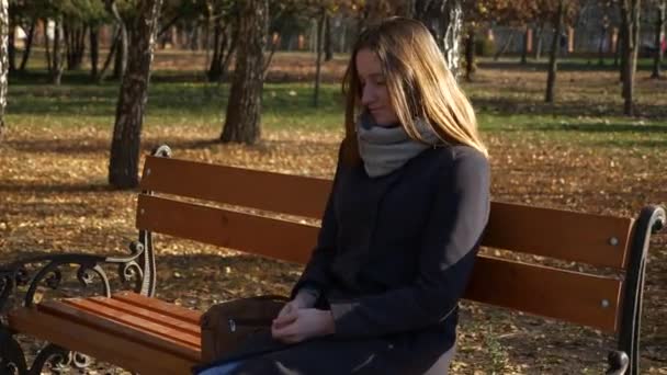 60P 漂亮的女孩坐在板凳上在公园等待约会 — 图库视频影像