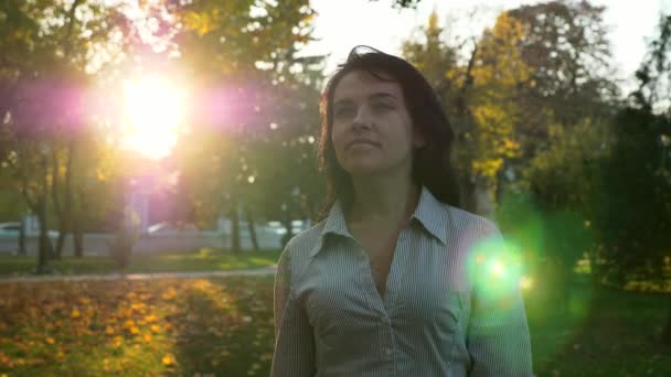 自信を持って美しい成功した女性は 都市公園と思考で歩きます 夕方日没の背景 都市公園における秋の晴れた日 レンズ フレア スローモーション Fps — ストック動画
