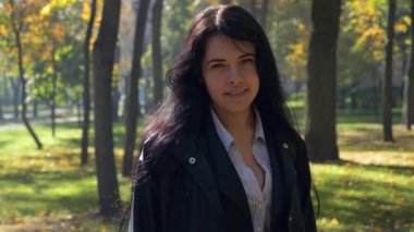 Şehir Parkı içinde gülümseyen güzel kız çevresinde kamera taşır. Sonbahar sabahı güneşli. 4 k yavaş hareket 60 fps