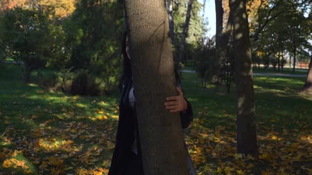 Escondendo Atrás Árvore Olhando Sorrindo Câmera Menina Alegre Bonita Anda — Vídeo de Stock