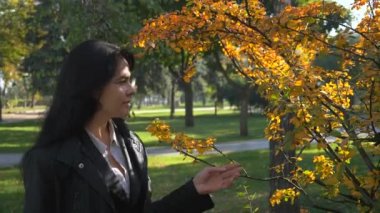 Ciddi güzel kız yürüyen Şehir Parkı ve düşünme. Sonbahar güneşli bir günde Şehir Parkı. Sabah güneş ışığı. Ağır çekim 60 fps