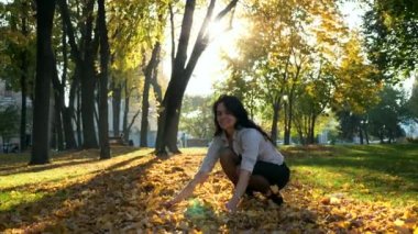 Mutlu kız sarı yapraklar hava atıyor. Düşen ağır çekim. Güzel bir akşam şehir parkı girsin. Mercek parlaması