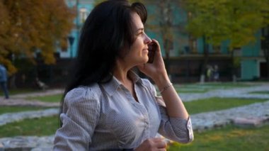 İş kadını akıllı telefon kullanarak sokakta yürüyor. Çalışma günü işe sonra Shift rahatlatıcı dinleniyor. Smartphone'da sohbet. Akşam şehir şehir. 4k yavaş hareket 60 fps