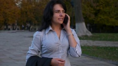 İş kadını akıllı telefon kullanarak sokakta yürüyor. Çalışma günü işe sonra Shift rahatlatıcı dinleniyor. Smartphone'da sohbet. Akşam şehir şehir. 4k yavaş hareket 60 fps