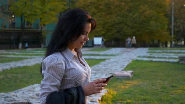 女商人走在大街上使用智能手机 下班后休息放松工作 在智能手机上聊天 晚上的城市市中心 慢动作 Fps — 图库视频影像