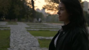 İşten sonra güzel kız akşam alacakaranlık parkta yürüyor. Sonbahar akşam şehir arka plan. 4 k yavaş hareket 60 fps