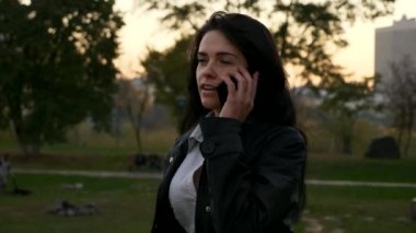 Successful Happy Woman Answers Call Talking on Smartphone. Walking In City Park. Autumn Summer Evening Morning Time