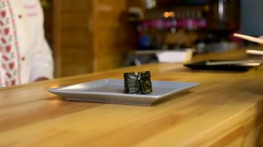 Kadın Elleri Çubukları Tutar ve Tabaktaki Yavaş Çekimde Suşi Yuvarlar. Bar Restoranı Akşam Yemeği