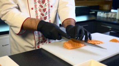 Mutfak Bıçak kesim somon kırmızı balık et dilimleri ile yakın çekim el. Şef aşçı Japon geleneksel Sushi ve restoranda Nigiri hazırlanıyor. Yemek pişirme için gıda katkı maddeleri