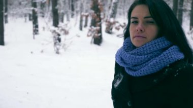 Hüzünlü güzel kız kış ormanda kar yağışı sırasında yürüyüş düşünüyorum. Doğa tatilde. Soğuk Frost hava. Kar ağaçlar ahşap kaplı. Ağır çekim 60 fps