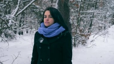 Hüzünlü güzel kız kış ormanda kar yağışı sırasında yürüyüş düşünüyorum. Doğa tatilde. Soğuk Frost hava. Kar ağaçlar ahşap kaplı. Ağır çekim 60 fps
