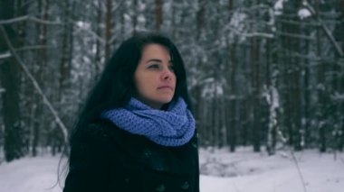 Hüzünlü güzel kız kış ormanda kar yağışı sırasında yürüyüş düşünüyorum. Doğa tatilde. Soğuk Frost hava. Kar ağaçlar ahşap kaplı. Ağır çekim 60 fps