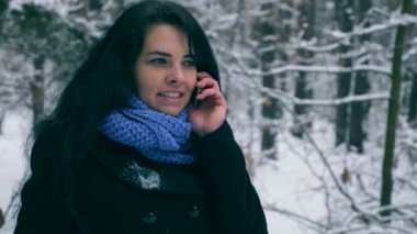 Güzel kız görüşmeler ormanın içinde cep telefonuyla çok soğuk. Soğuk Frost hava kar ağaçlar ahşap kaplı