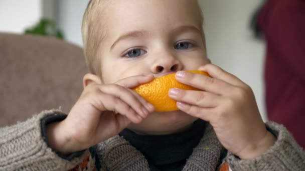 Cute Little Boy Eats Tasty Orange Kitchen Blurred Background Parents — Stock Video