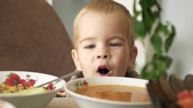 Mutfak masasında oynayan neşeli küçük çocuk gülümsüyor. Mutlu gülen çocuk. Üzerinde bulanık arka plan yemek sırasında Evet anne. 4 k yavaş hareket 60 fps