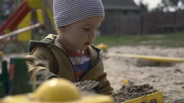 严重可爱的孩子独自玩破碎的玩具沙盒 一个小男孩在农村游乐场玩沙地 乡村生活 夏季秋风晴天 — 图库视频影像