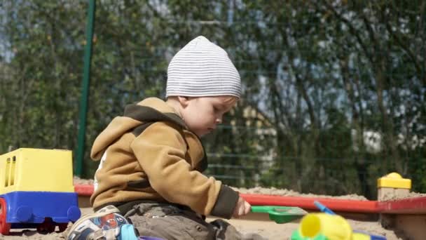 うれしそうな幸せな子供グッズ シャベルと子供用のサンド ボックス内で再生されます 田舎暮らし 夏秋の晴れた日 スローモーション — ストック動画