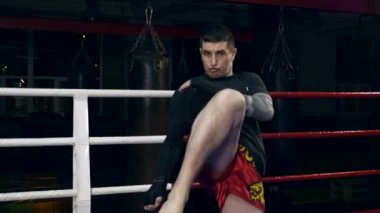 Ağır çekim yakın çekim Muay Tay savaşçı boksör şiddetle atma yumruk ve tekme kamera ile bir yoğun Look onun yüzünde. Eğitim spor salonunda boks ringde