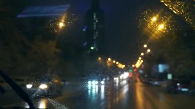 Gece sürüş. Şehir sokak ve durak hareketli araba kırmızı ışık sinyal kavşak üzerinde. Ön cam görünümünden arabanın içine. Bulanık araçlar kentsel yolda. Kış akşam kar yağışı yavaş hareket 0,5 hızı 50fps