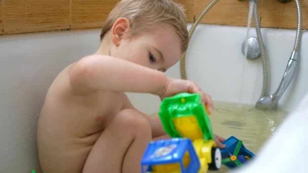 幸せなうれしそうな子は バスタブの水のおもちゃで笑顔を果たしています かわいい男の子の浴室で楽しい時を過します スローモーション Fps — ストック動画