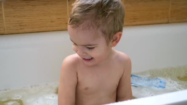 幸せなうれしそうな子は バスタブの水のおもちゃで笑顔を果たしています かわいい男の子の浴室で楽しい時を過します スローモーション Fps — ストック動画