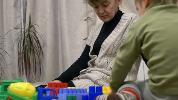 祖母和孙子玩玩具建设者砖在房间里在家里 — 图库视频影像