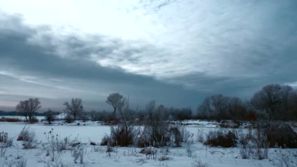 パノラマの夜の冬の風景 平野の田舎の道に沿って移動します 雪の上に曇り空では フィールドと川を覆われています 年末年始の寒さ — ストック動画